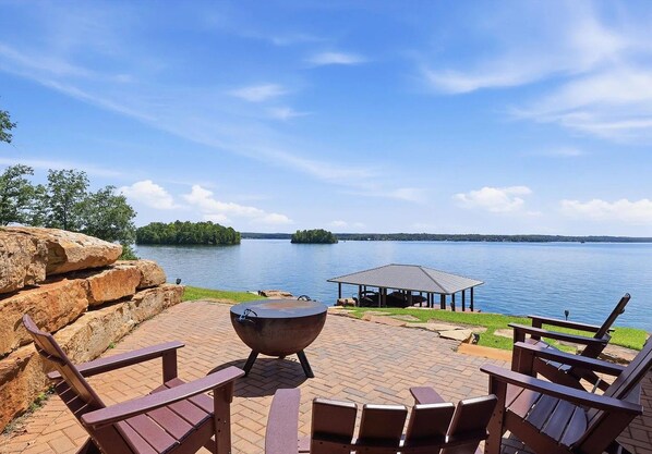 A lakeside patio with outdoor seating and a fire pit.