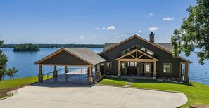 Une maison à deux étages avec un porche couvert, un garage et une vue sur un lac.