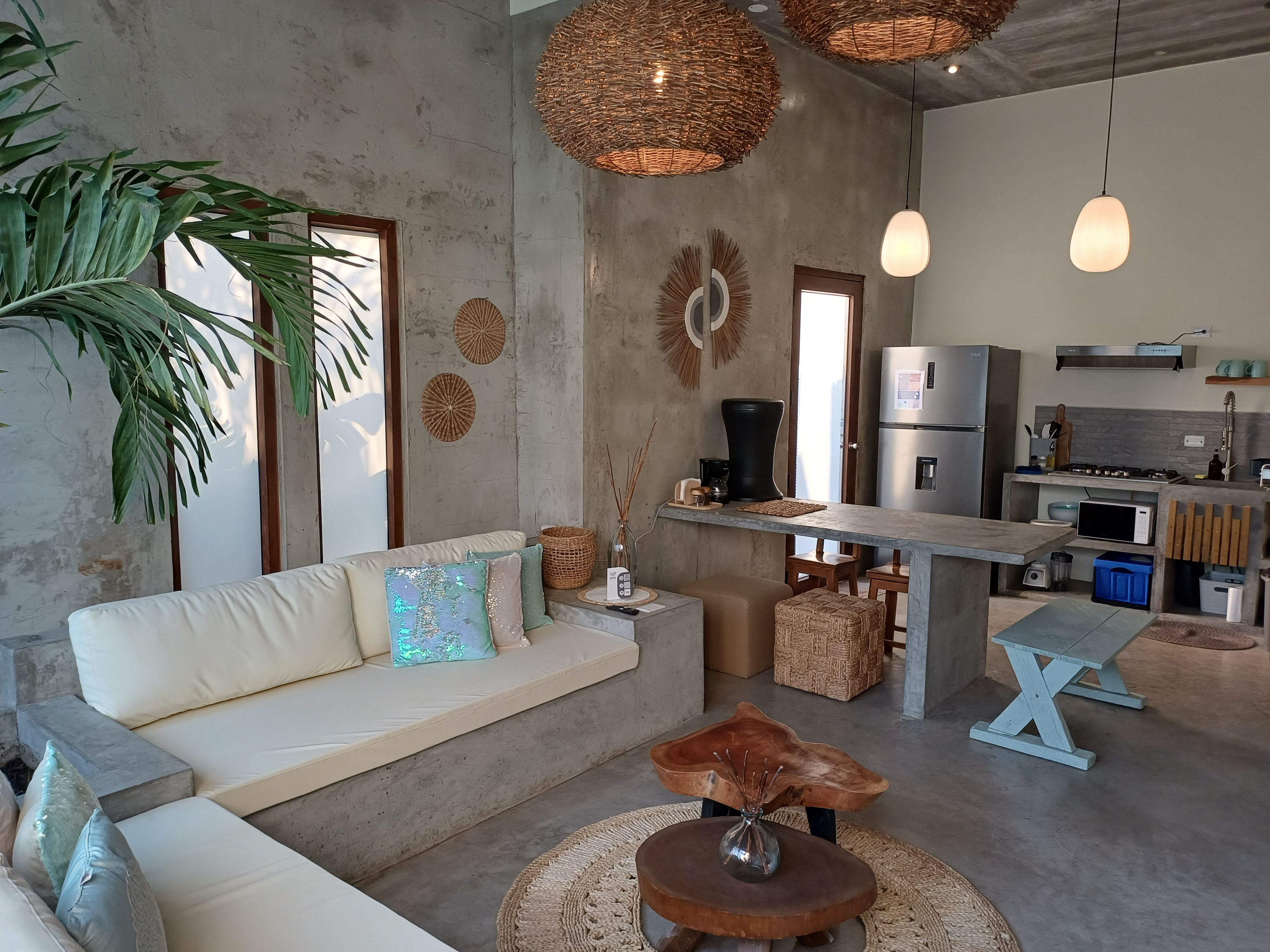 Una sala moderna con un sofá, una mesa de centro y una zona de cocina con refrigerador y microondas.