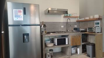A modern kitchen with a stainless steel refrigerator, a built-in microwave, a gas stove, and a toaster.