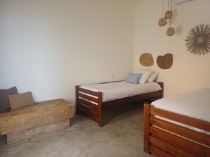 Un dormitorio con una cama individual, un banco de madera y una lámpara fijada en la pared.