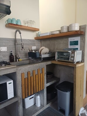 Una cocina compacta con lavavajillas integrado, un tostador y estantes de madera sobre la encimera.