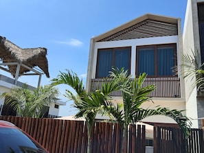 A modern two-story building with a balcony, surrounded by a wooden fence and tropical plants. - Areia Bali: A/C, private pool, just steps from the ocean (El Paredón Buena Vista)