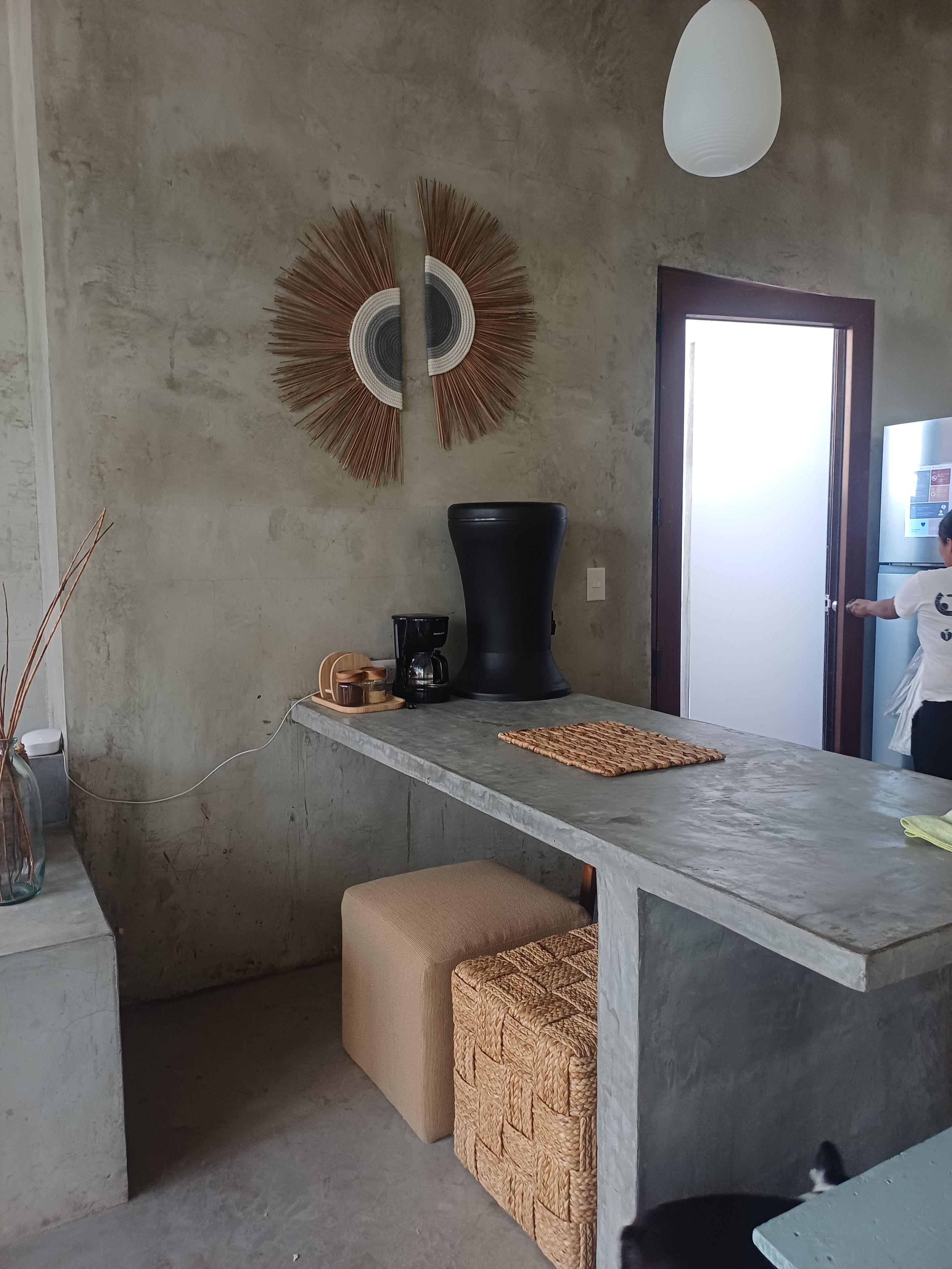 A modern kitchen with a concrete countertop, a coffee machine, and a woven basket.