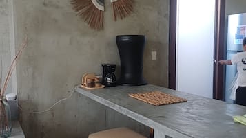 A modern kitchen with a concrete countertop, a coffee machine, and a woven basket.