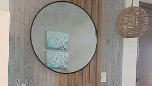 Un baño con un espejo grande, un revestimiento de pared de madera, un lavamanos, un dispensador de jabón y una cesta tejida.