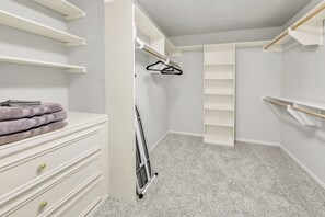 Ein begehbarer Kleiderschrank mit offenen Regalen, einer Kleiderstange und einem Stapel gefalteter Handtücher.
