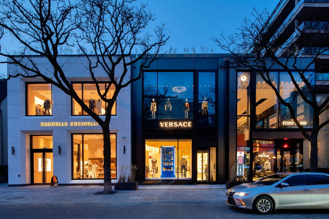 Een modern gebouw met etalages voor Brunello Cucinelli en Versace.