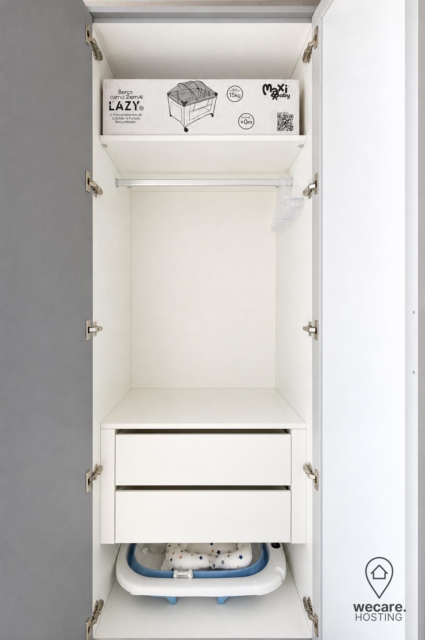 Un armario blanco con cambiador para bebés integrado, que incluye un cajón y un área para colgar ropa con un colchón cambiador.