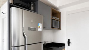 Eine moderne Küche mit einem Edelstahl-Kühlschrank, einer Mikrowelle und einer schwarzen Arbeitsplatte.