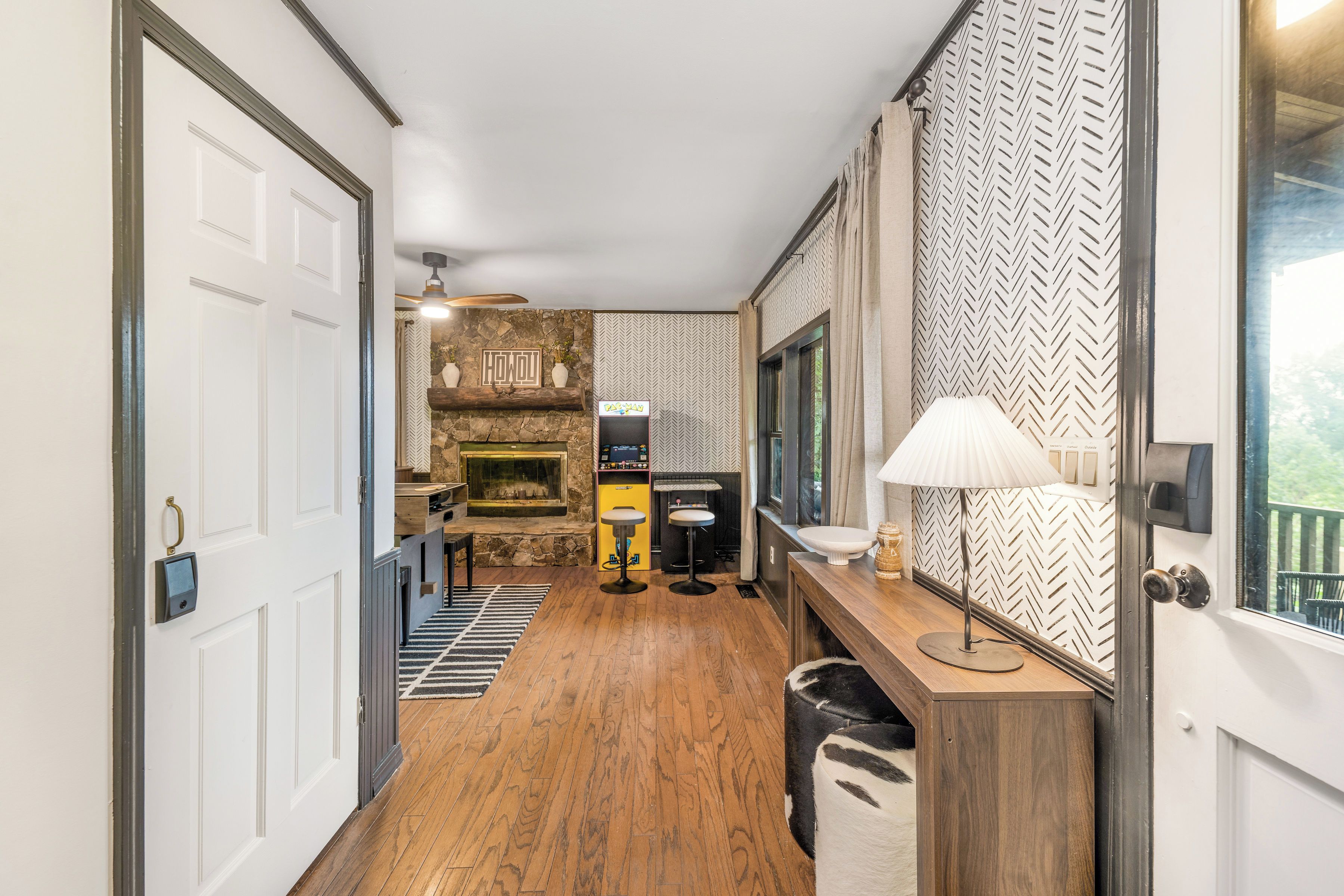 A hallway with a stone fireplace, a bar area, and a wooden floor.