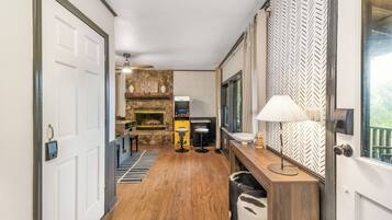 A hallway with a stone fireplace, a bar area, and a wooden floor.