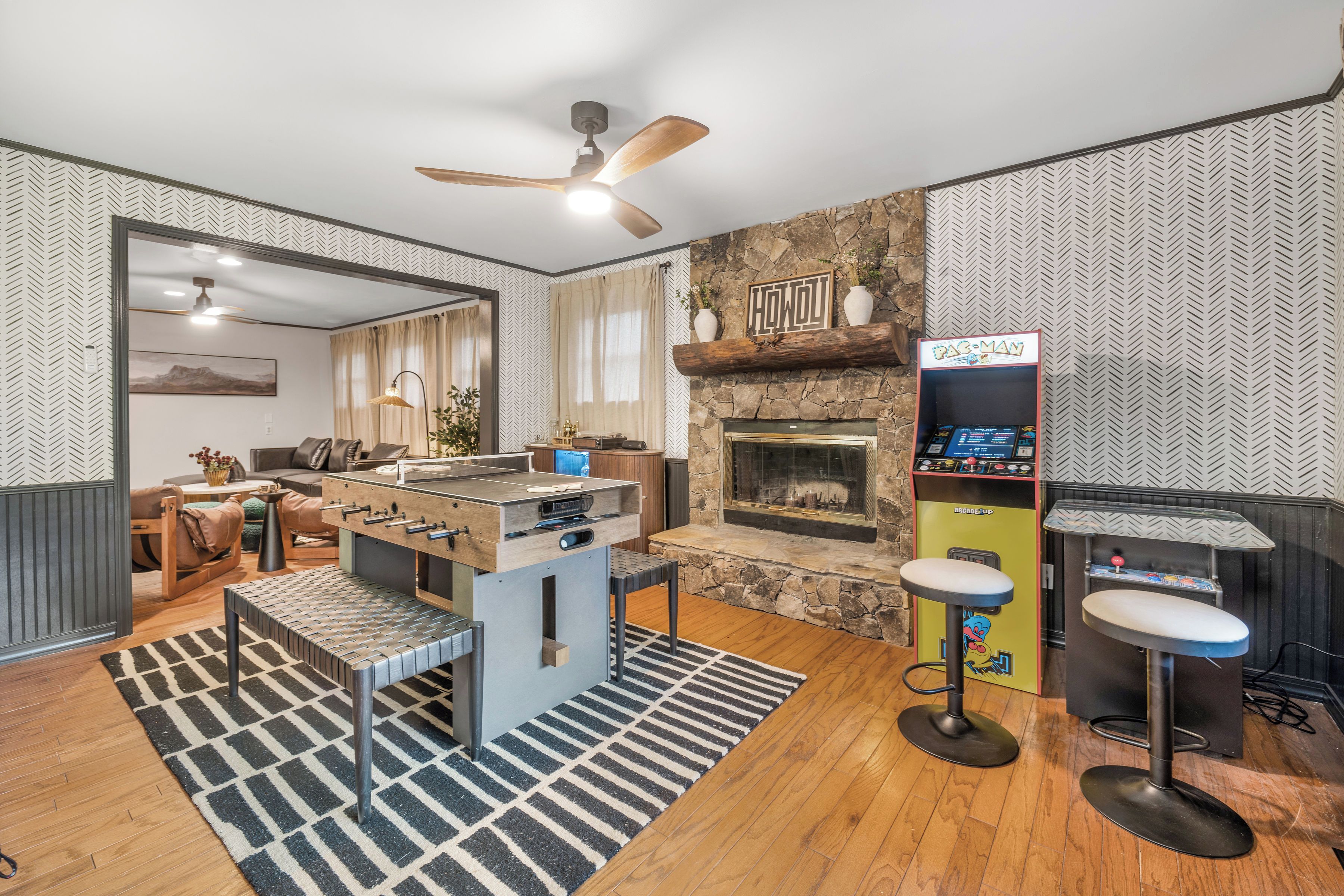 A modern living room with a foosball table, a fireplace, and a retro arcade machine.