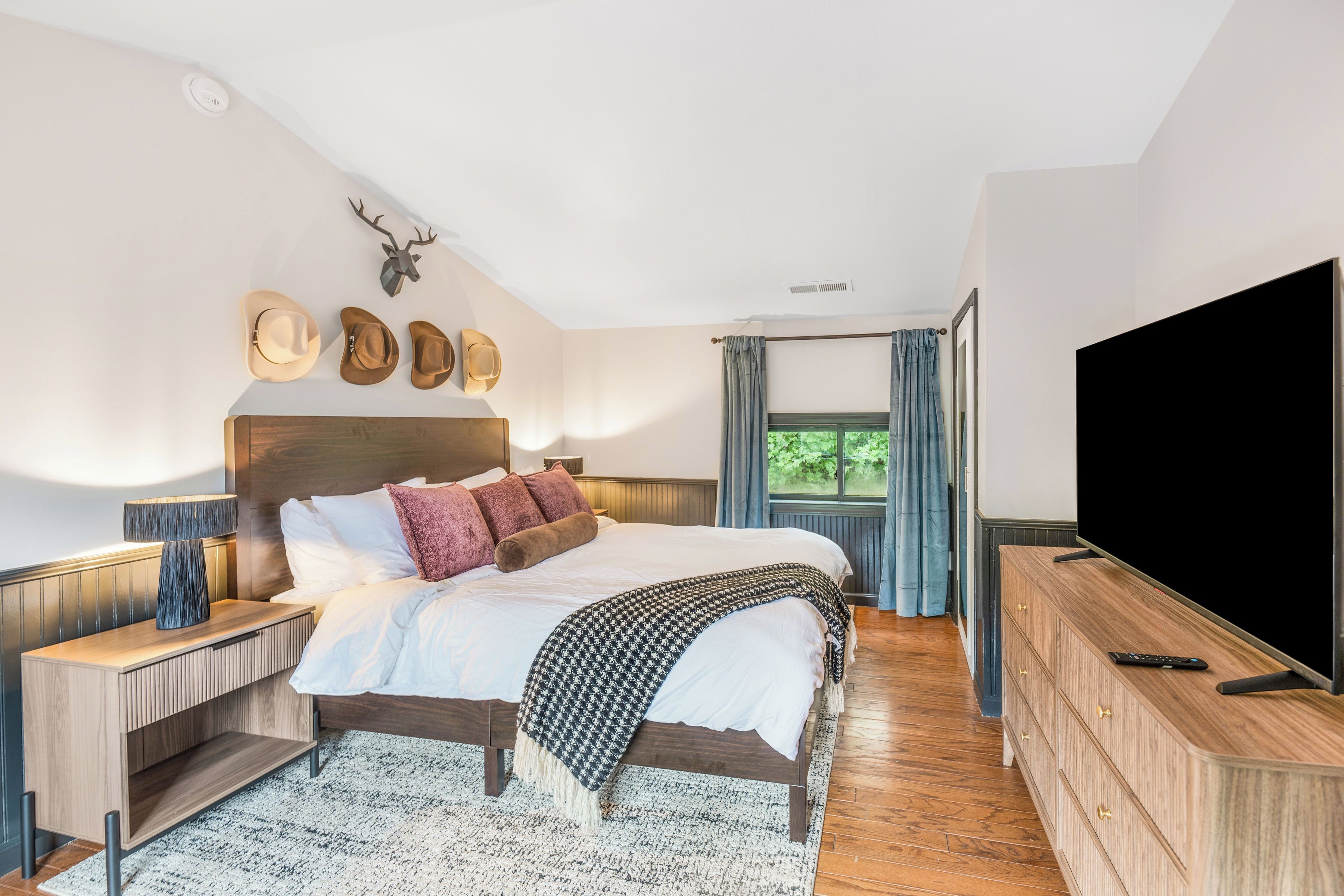 A modern bedroom with a large bed, wooden headboard, and a television.