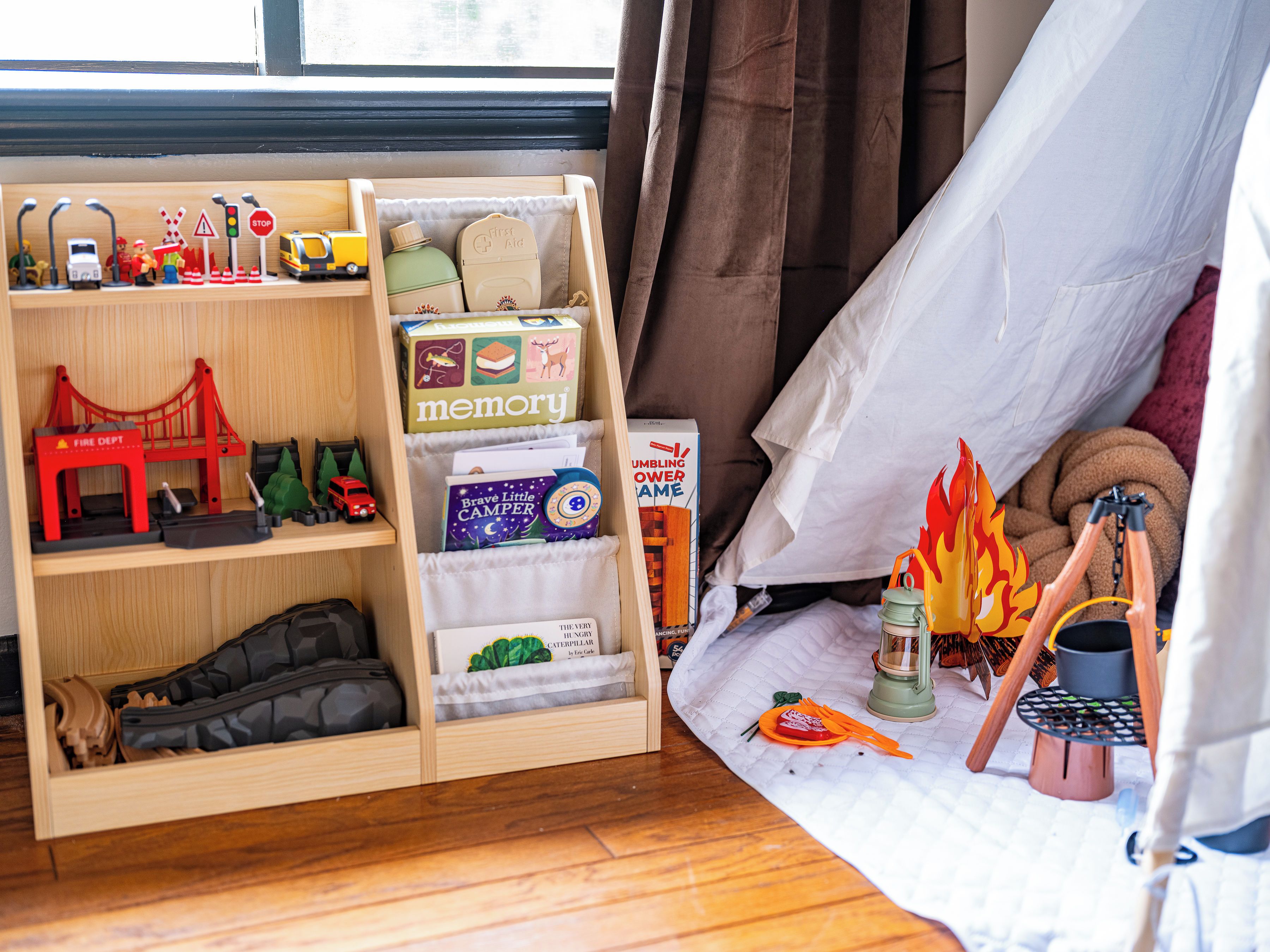 A child's play area with a wooden shelf containing toys and books.