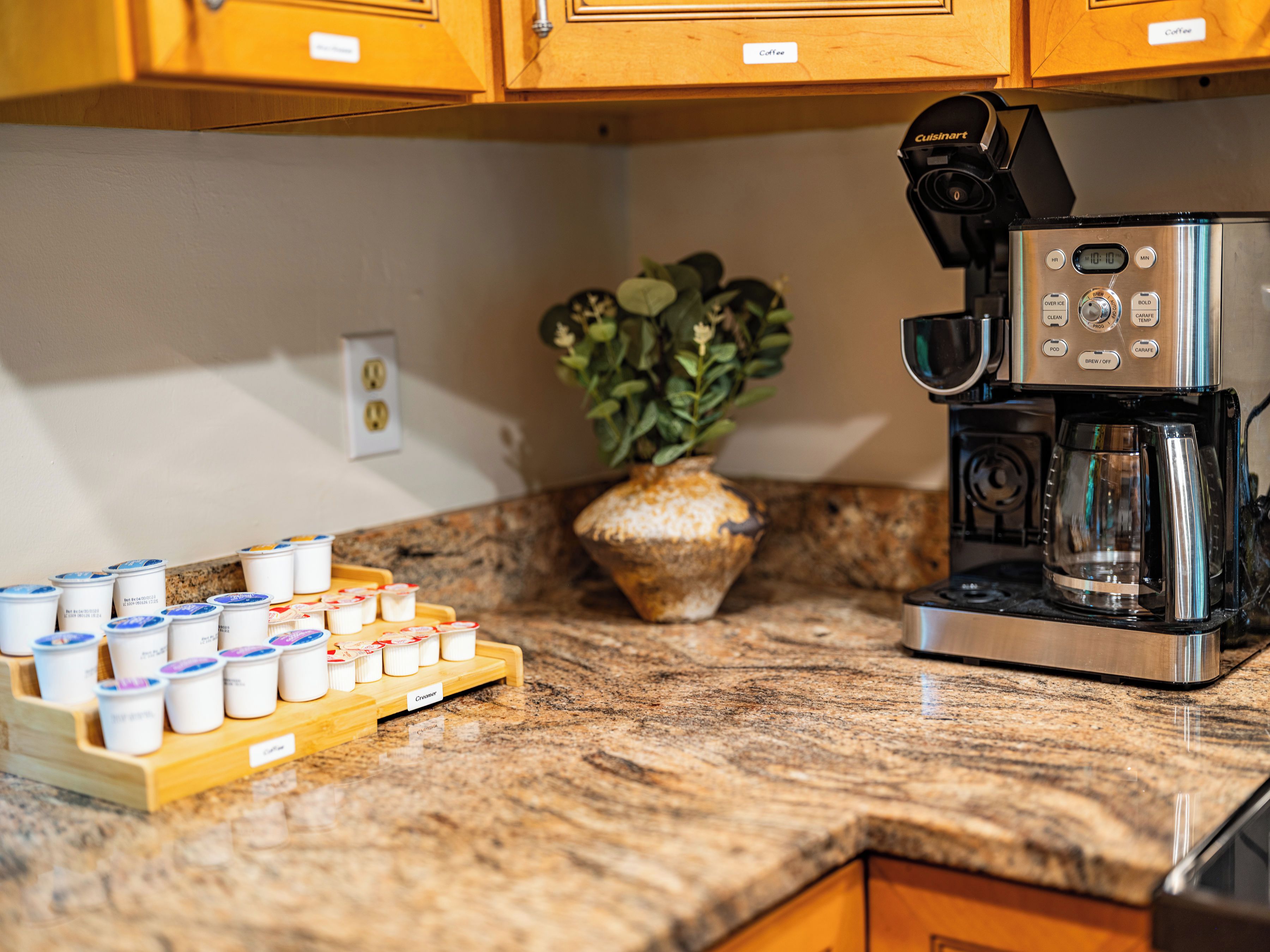 A kitchen with a coffee machine, a plant, and a tray of coffee pods.