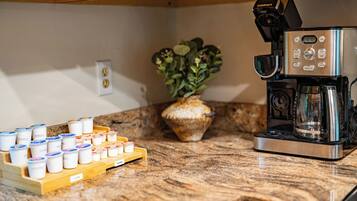 A kitchen with a coffee machine, a plant, and a tray of coffee pods.