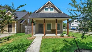 Une maison d’habitation avec un porche à l’avant, une allée et une pelouse bien entretenue.