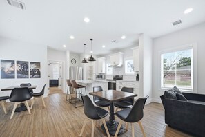 A modern kitchen with white cabinets, a central island, and a dining area with a wooden table and black chairs. - Sterling-2 Min Drive to Texas A&M, Comfy King Beds (College Station)