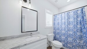 Une salle de bain avec un lavabo blanc, un miroir, des toilettes et un rideau de douche.