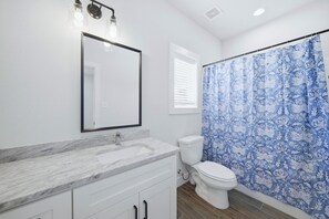 A bathroom with a white sink, a mirror, a toilet, and a shower curtain. - Sterling-2 Min Drive to Texas A&M, Comfy King Beds (College Station)
