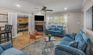A living room with a sofa, armchair, and coffee table. There is a fireplace and a ceiling fan. - Walton: 60 Second Drive to Texas A&M (College Station)