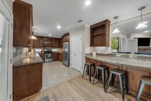 A modern kitchen with wooden cabinets, stainless steel appliances, and a granite countertop. - Walton: 60 Second Drive to Texas A&M (College Station)