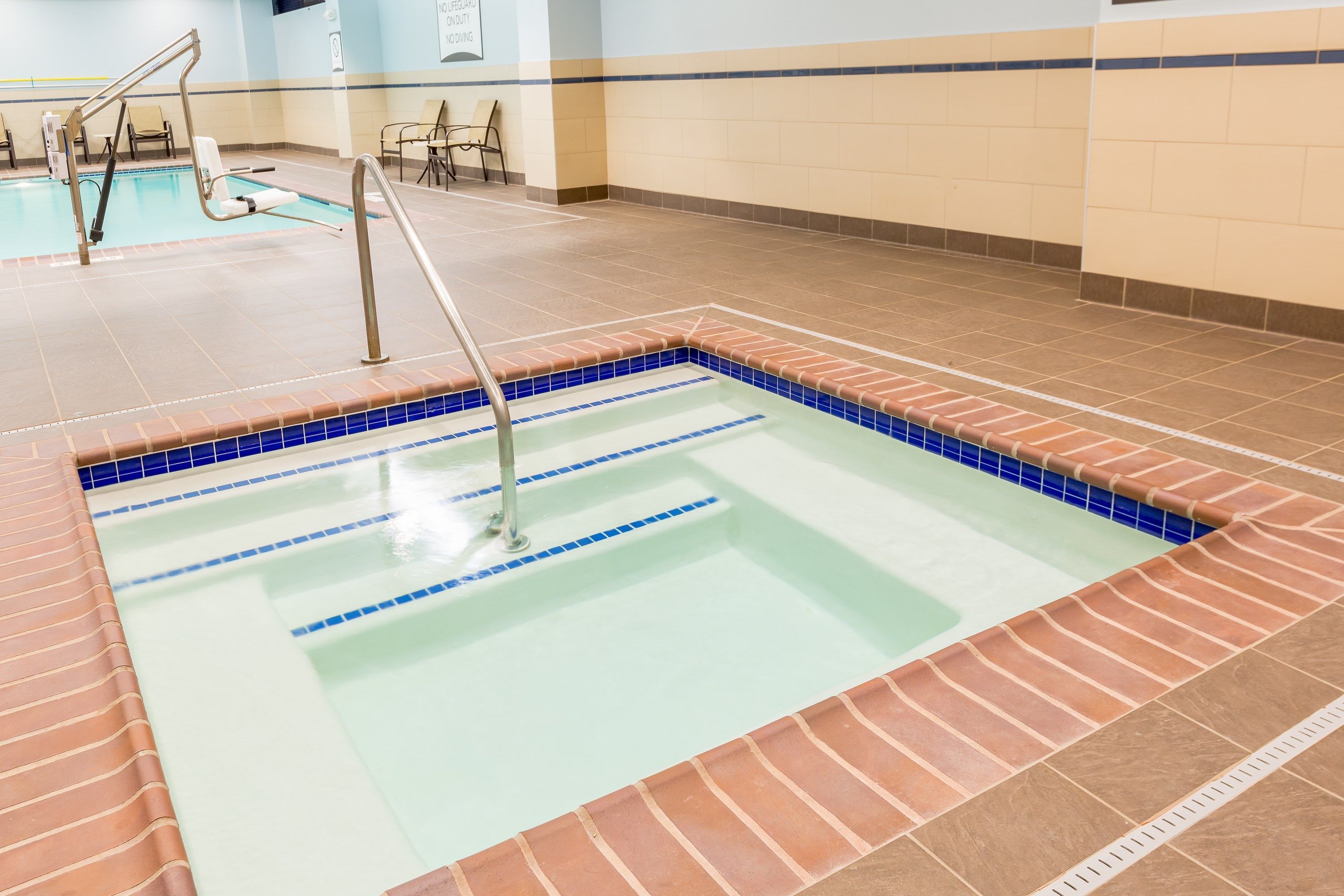 En indendørs swimmingpool med tydelige baner, flisekant og metalgelænder.