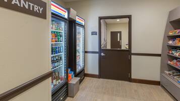 A hotel pantry with refrigerated drinks, snacks, and a sign indicating it's for staff use only.