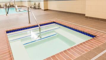 Une piscine intérieure avec des couloirs bien délimités, un bord carrelé et une rambarde métallique.