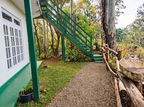 A staircase leading to a building with a green exterior and a window with multiple panes.