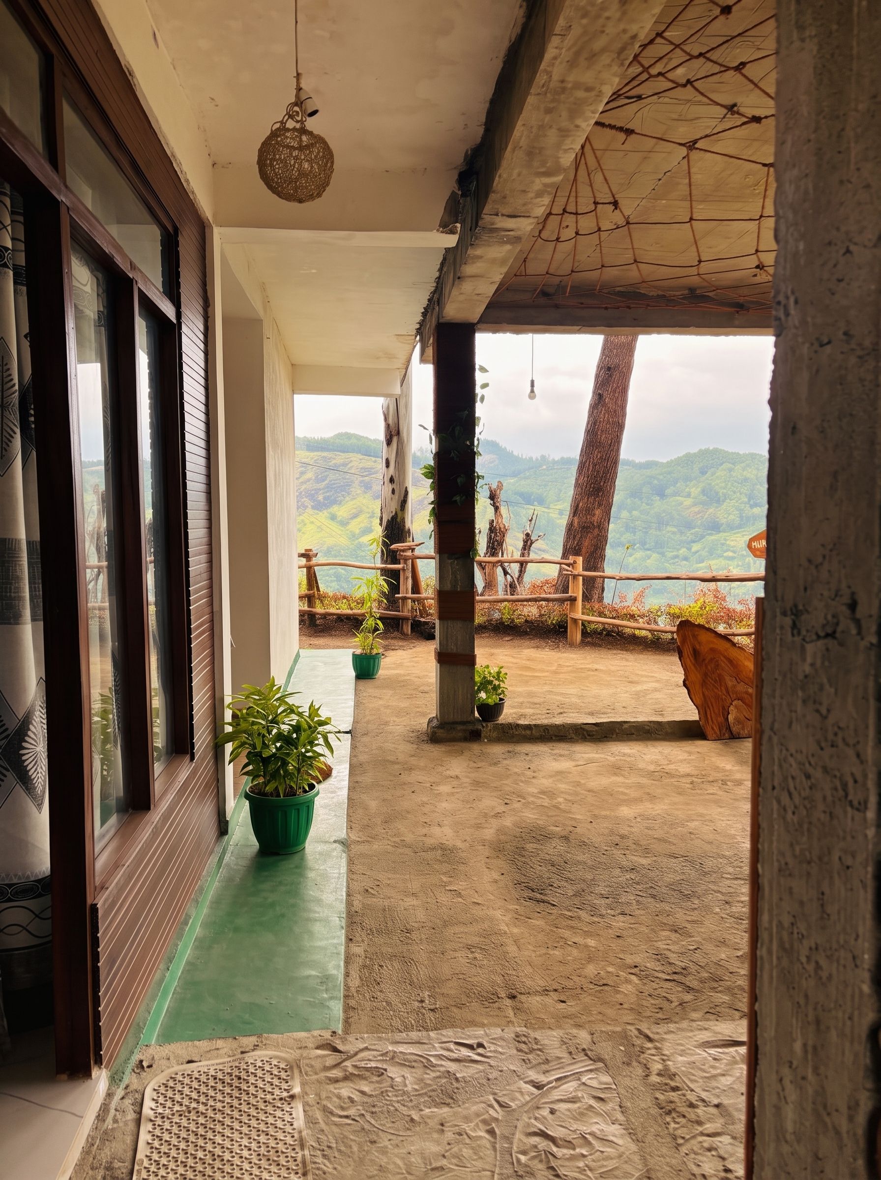 Un balcón con vistas a un paisaje montañoso, plantas en macetas y una cerca de madera.