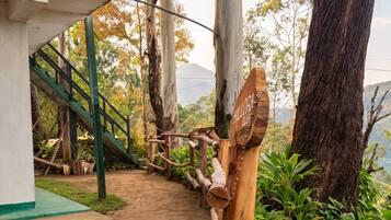 A dirt path leading to a staircase with a metal railing, surrounded by trees and greenery.
