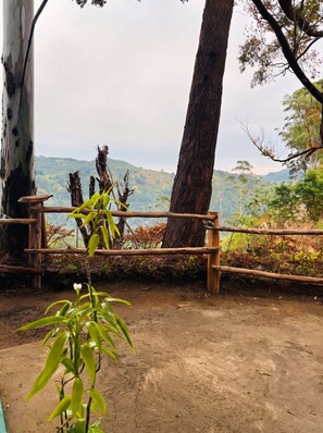 A dirt path leading to a wooden fence overlooking a hilly landscape.