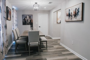 A dining area with a wooden table and chairs, a chandelier, and artwork on the walls. - 7 BRs 3 BAs - 10 beds! (Groves)