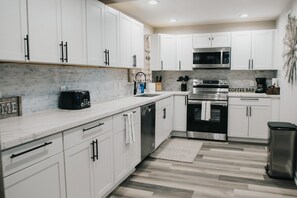 A modern kitchen with white cabinets, a microwave, a coffee bar, and a dishwasher. - 7 BRs 3 BAs - 10 beds! (Groves)