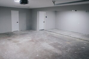 A room with two white doors, a concrete floor, and a ceiling with a visible light fixture. - 7 BRs 3 BAs - 10 beds! (Groves)