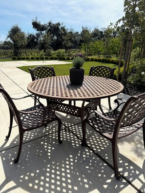 An outdoor patio with a round metal table and four chairs, surrounded by a garden. - Modern Farmhouse Retreat
Woodbridge Wine Country (Woodbridge)