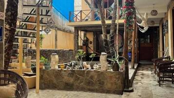 Un patio interior con suelo de piedra, una escalera y diferentes plantas y muebles.