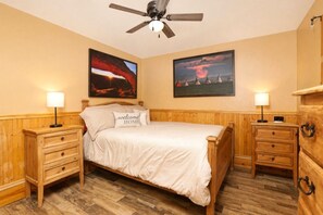 Un dormitorio con una cama de madera, dos mesitas de noche, un ventilador de techo y dos lámparas de pared.