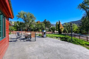 A patio area with outdoor seating, a barbecue grill, and a trash can. - Cozy, Family Cabin-Style Home, Walk to River & Downtown, Dog Friendly (Glenwood Springs)