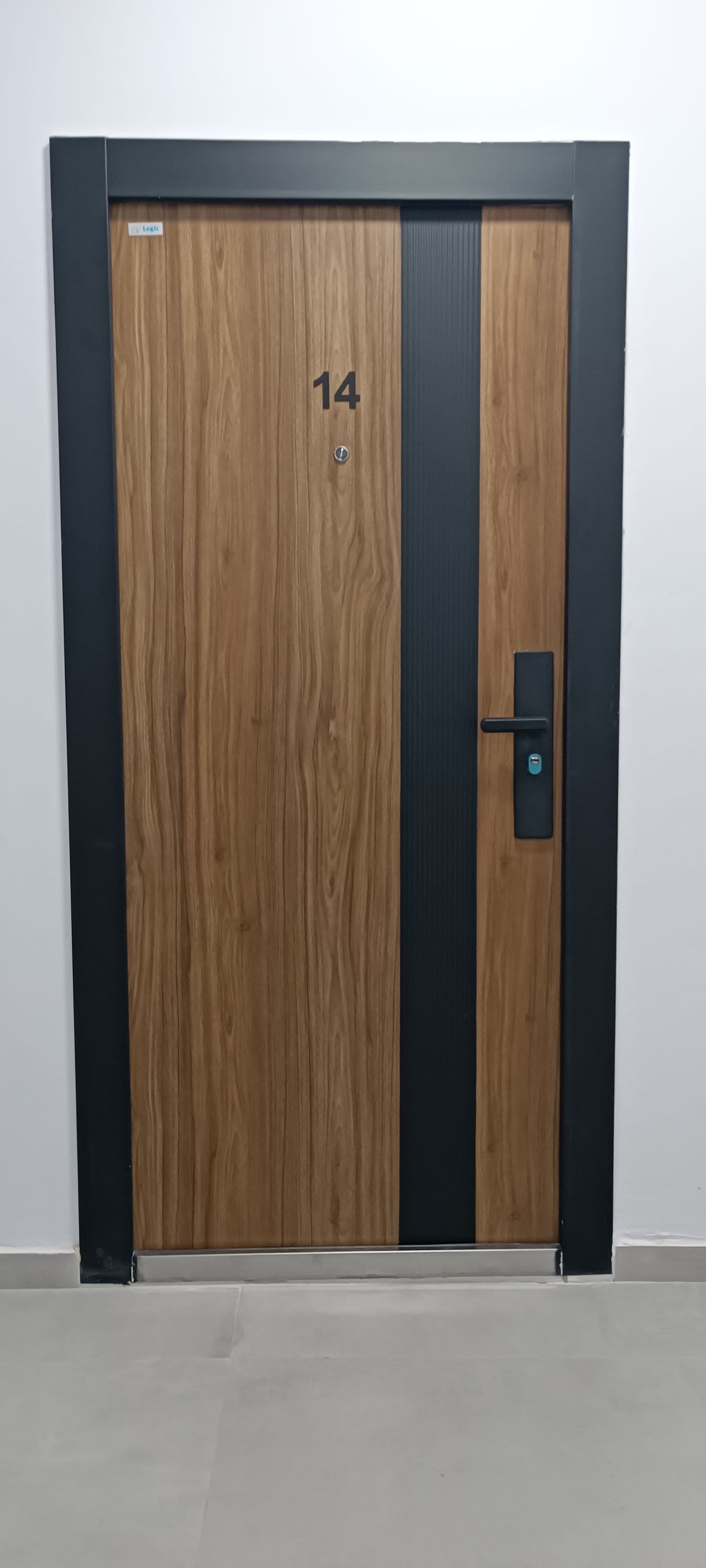 Eine Holztür mit der Nummer 14, einem schwarzen Streifen und einem modernen Türgriff.