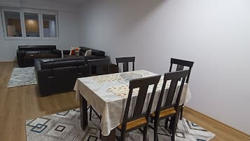 A dining area with a table set for four, surrounded by chairs.