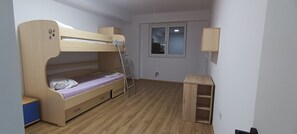 A bunk bed with a ladder, a small desk, and a window.