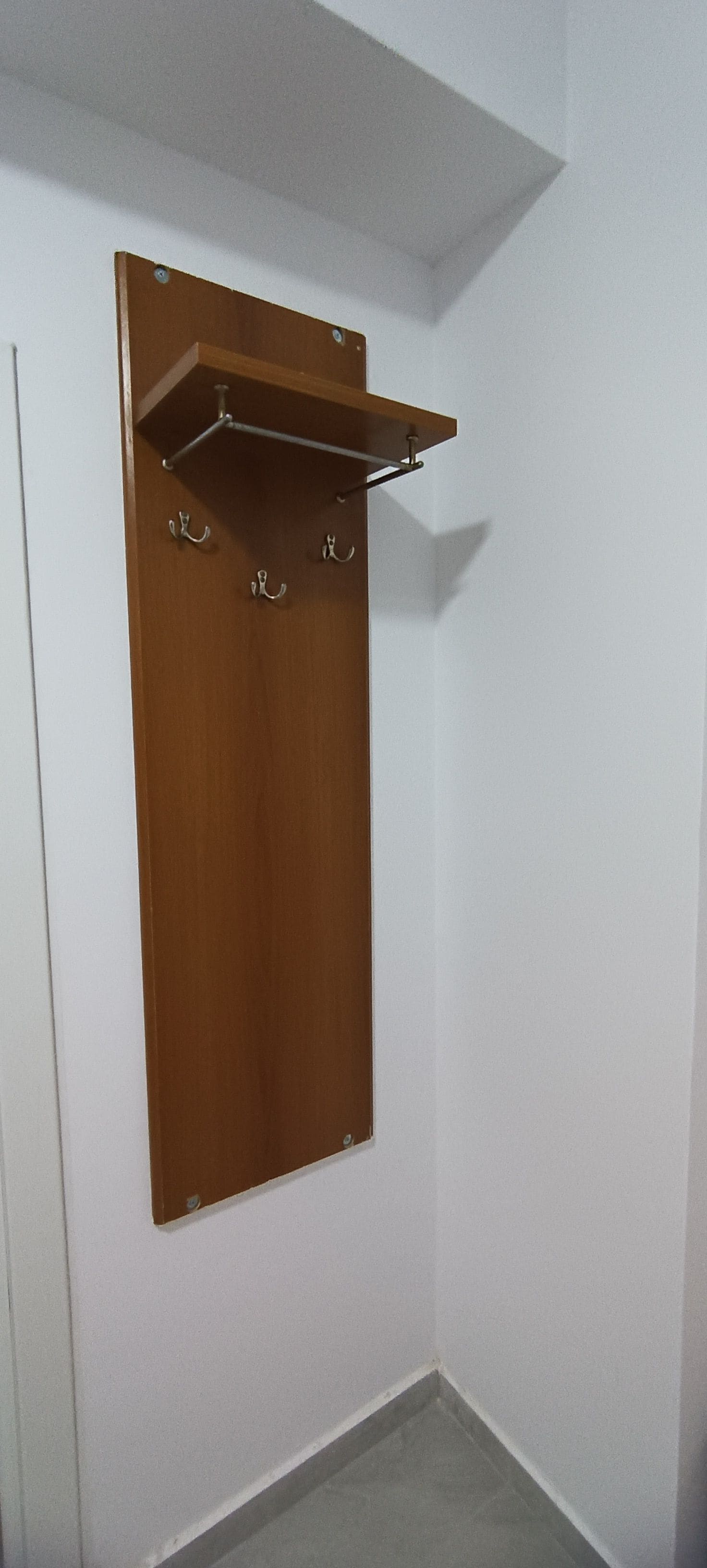 A closet with a wooden door, a metal rod, and a metal shelf.