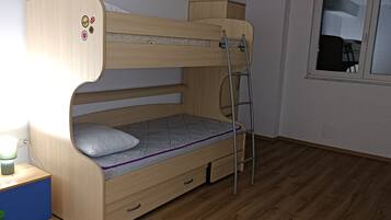 Un lit superposé avec une échelle, une table de chevet avec une lampe et une fenêtre dans la pièce.