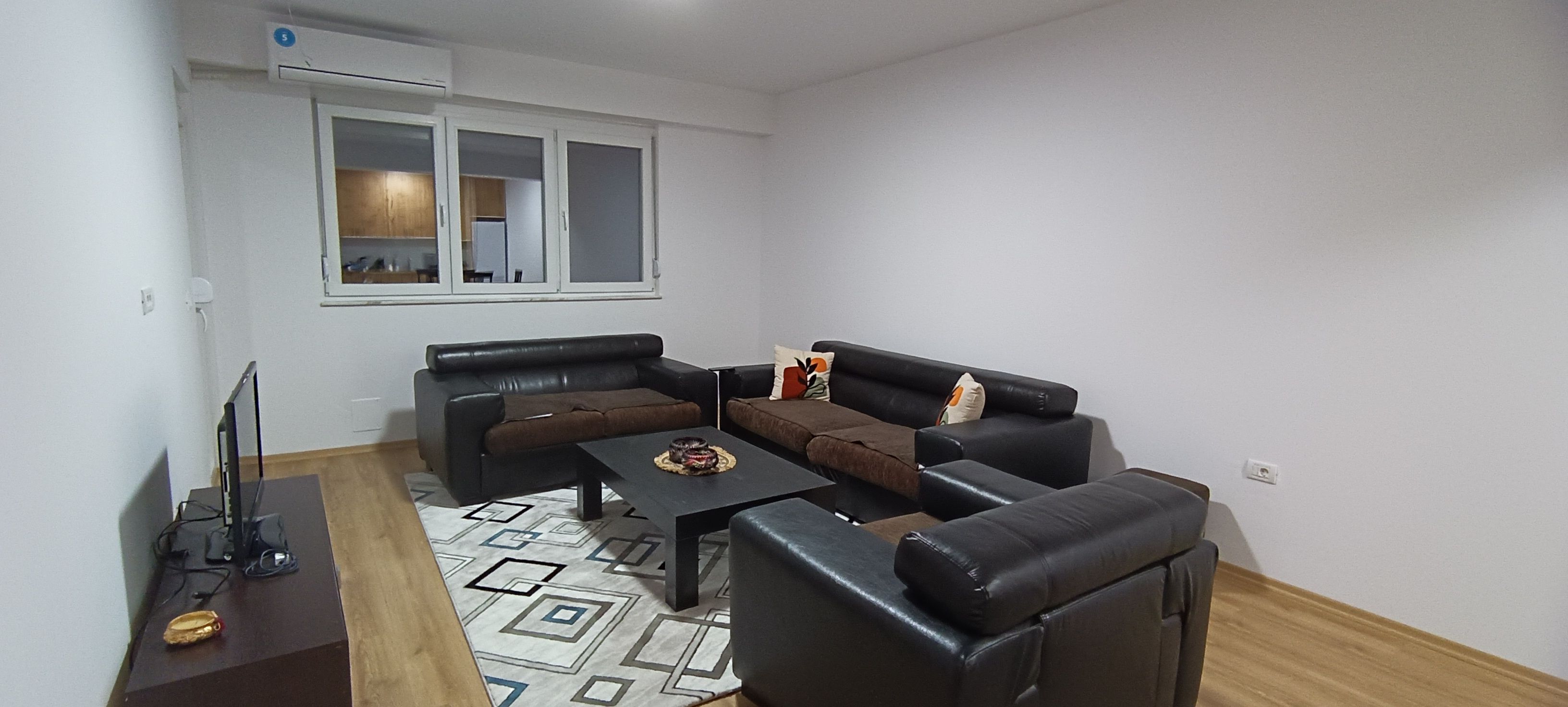 Een moderne woonkamer met een hoekbank, een salontafel en een flatscreen televisie.