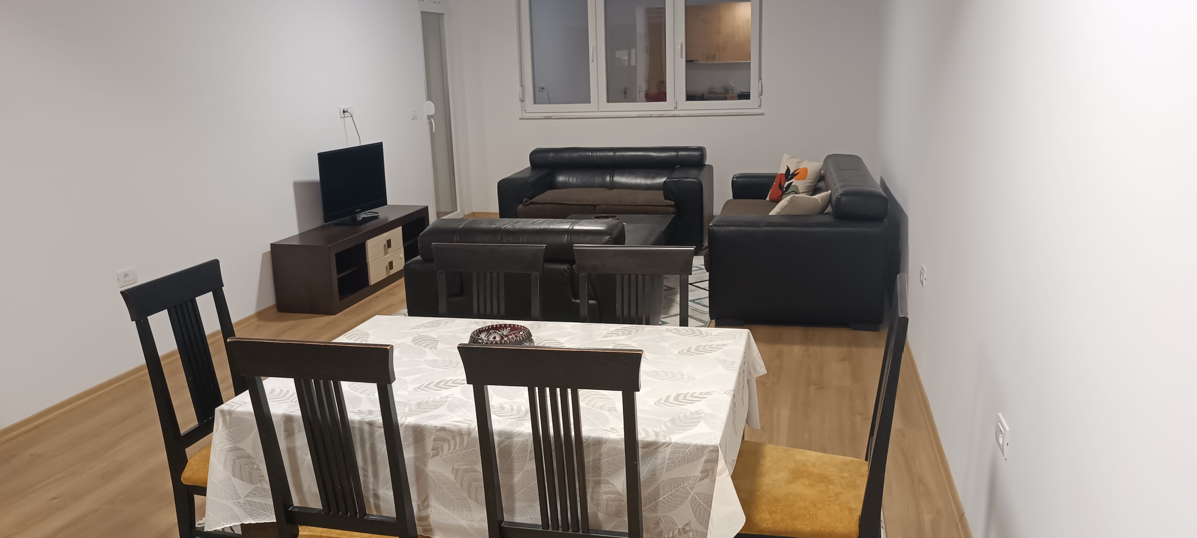 Un espacio habitable compacto con una mesa de comedor, sillas, un sofá, un televisor y un mueble pequeño.