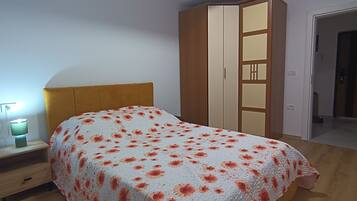 Un dormitorio con una cama, una mesita de noche, un armario y una puerta que da a otra habitación.