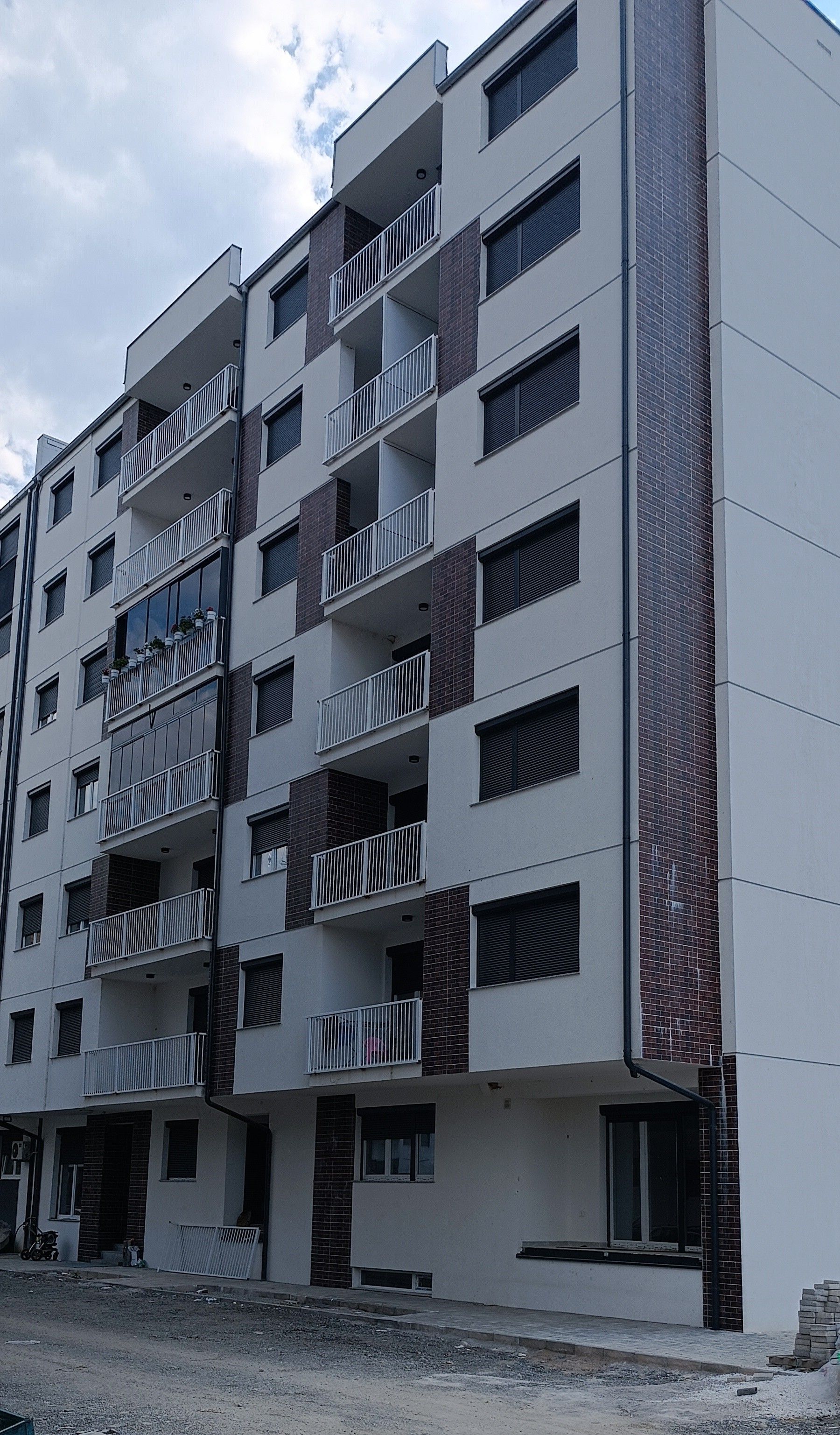 Un immeuble résidentiel à plusieurs étages, doté de balcons, de fenêtres et d’une façade en briques.